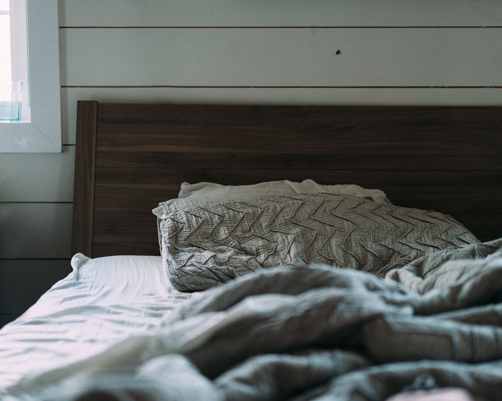 Primary bedroom with a wood headboard and soft grey linens
