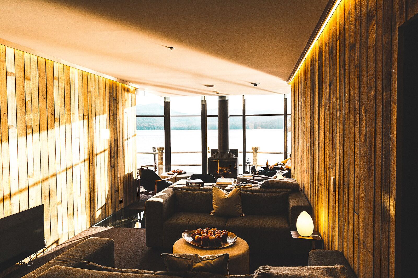 Warm, wood-paneled living room with deep sofas and evening light